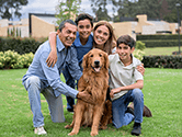 A happy family with two kids and a dog pose for a picture in their backyard