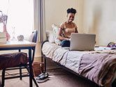 A young woman uses her laptop in her college dorm room