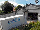 A 1-800-PACK-RAT portable storage container sits in a home's driveway open as homeowners put belongings inside it