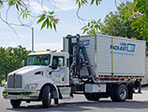 A 1-800-PACK-RAT mini-mover truck is on its way to deliver a portable storage container to a customer