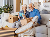 An older couple examines their belongings as they place them inside of a box for their move