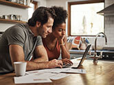 A couple looks at a laptop while making important decisions