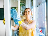 A woman washes a window inside her home