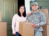 A woman and her military service member husband bring boxes into their new home