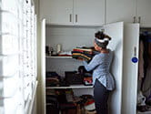 A woman puts away folded clothes into a closet