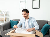 A man packs items in a box with bubble wrap