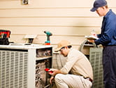 Technicians look at a home's air conditioning unit