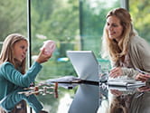 Mom on computer while daughter counts change from piggy bank