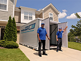 Workers stand in front of an open 1-800-PACK-RAT portable storage container